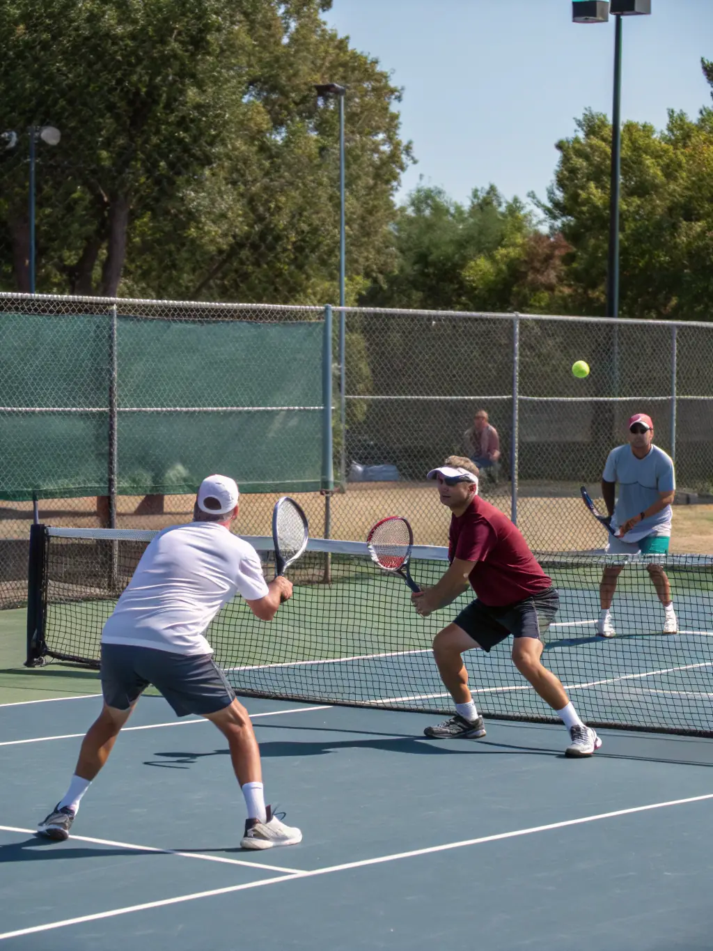 Adult tennis players enjoying a recreational doubles match on a sunny day at CDS Lioran Club Sports Tennis.